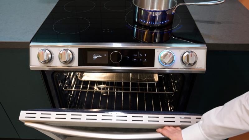 A product expert demonstrates the oven beneath an electric induction stove cooktop during a preview of Samsung Electronics Co.s Bespoke Home appliances