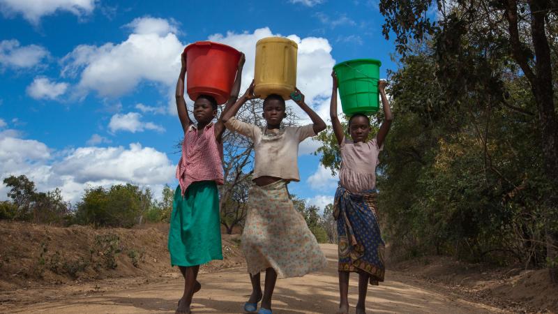Girls carrying water buckets at a borehole in Malawi