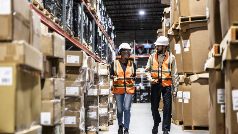 Warehouse employees walking in aisle of warehouse