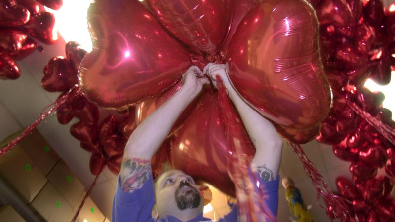 Party City assistant manager, Brian Noll,(cq), 31 of Tustin, gathers a dozen red heart shaped balloons