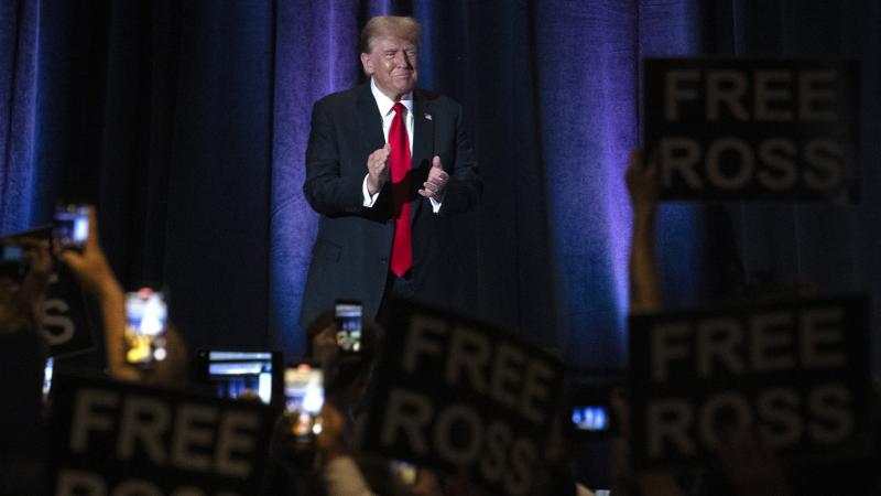 People hold up signs reading "Free Ross" as former US President and Republican presidential candidate Donald Trump arrives to address the Libertarian National Convention in Washington, DC, May 25, 2024. 