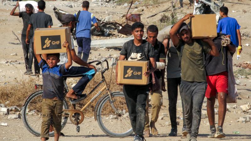 Boys walk with boxes of humanitarian aid they received at a distribution centre run by the US and Israeli-backed Gaza Humanitarian Foundation