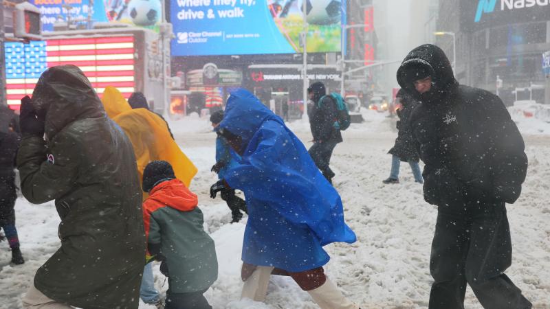 People walk along Broadway in Times Square amid a blizzard on February 23, 2026 in New York City.