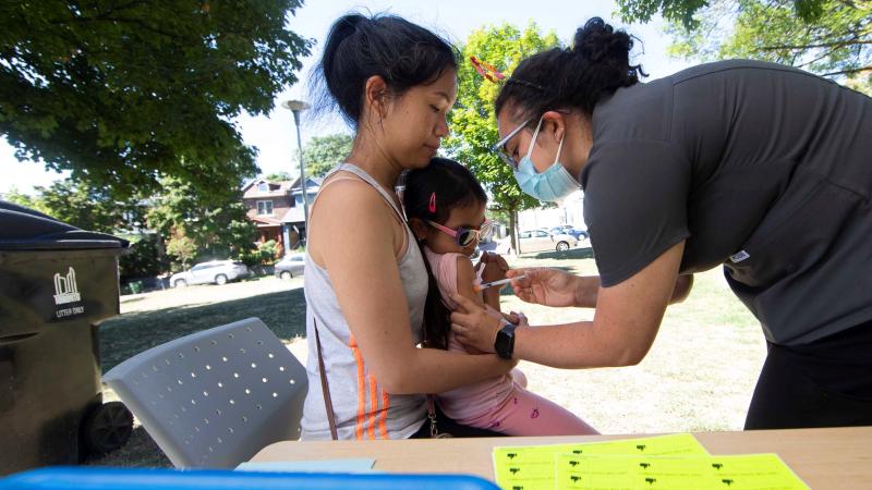 A girl receives a COVID-19 vaccine with the help of her mother at a COVID-19 vaccination site in East Lynn Park in Toronto, Canada, Aug. 12, 2022.