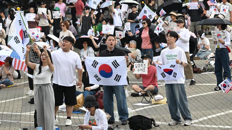 South Korean protesters wave the national flags outside a vote-counting centre in Seoul on June 10, 2026, to call for a rerun