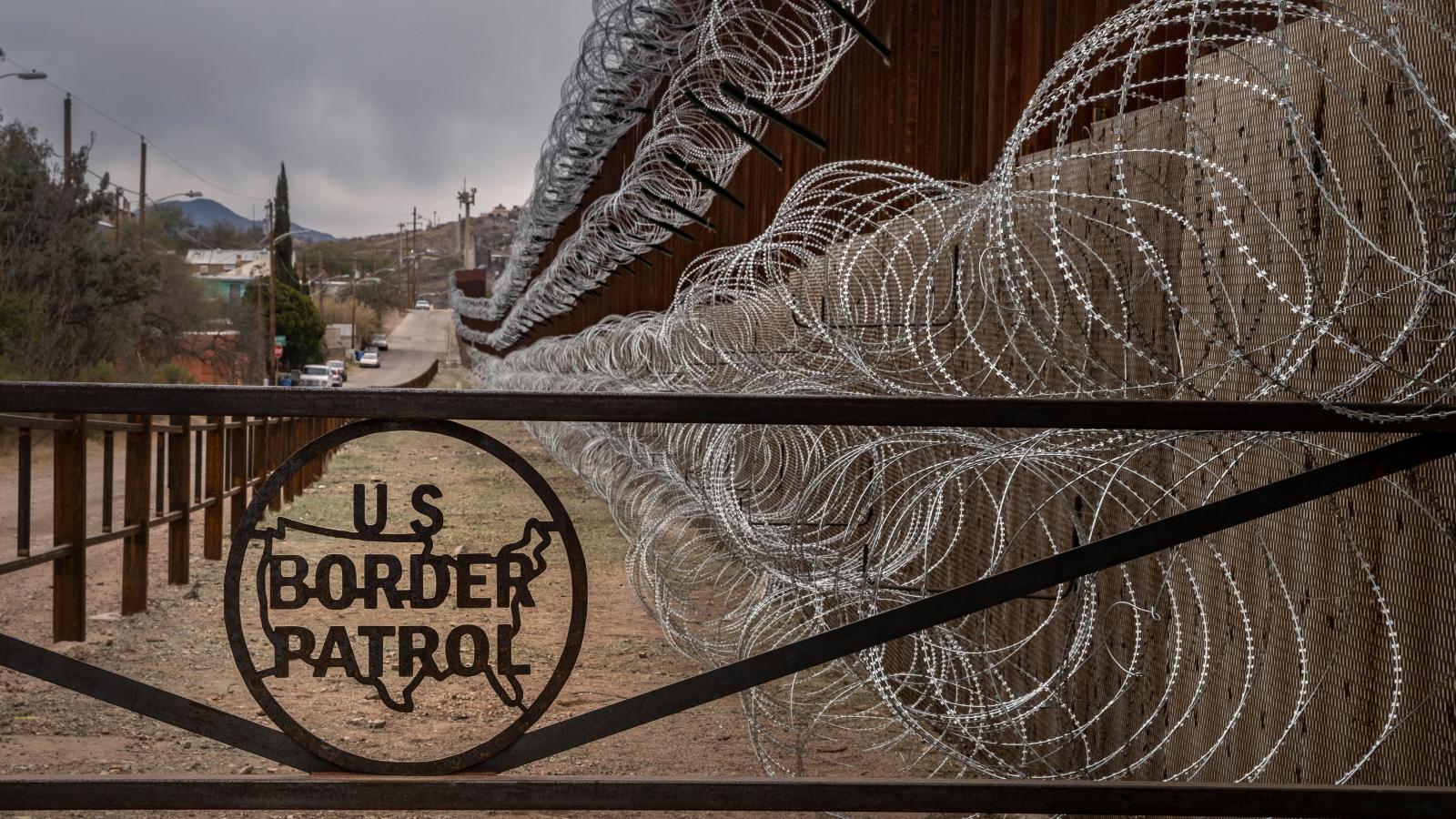 A metal fence marked with the US Border Patrol sign at the US/Mexico border fence, in Nogales, Arizona.