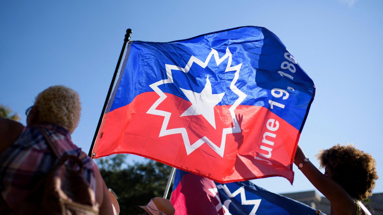 People carry a Juneteenth flag as they march during a Juneteenth re-enactment celebration in Galveston, Texas, on June 19, 2021.