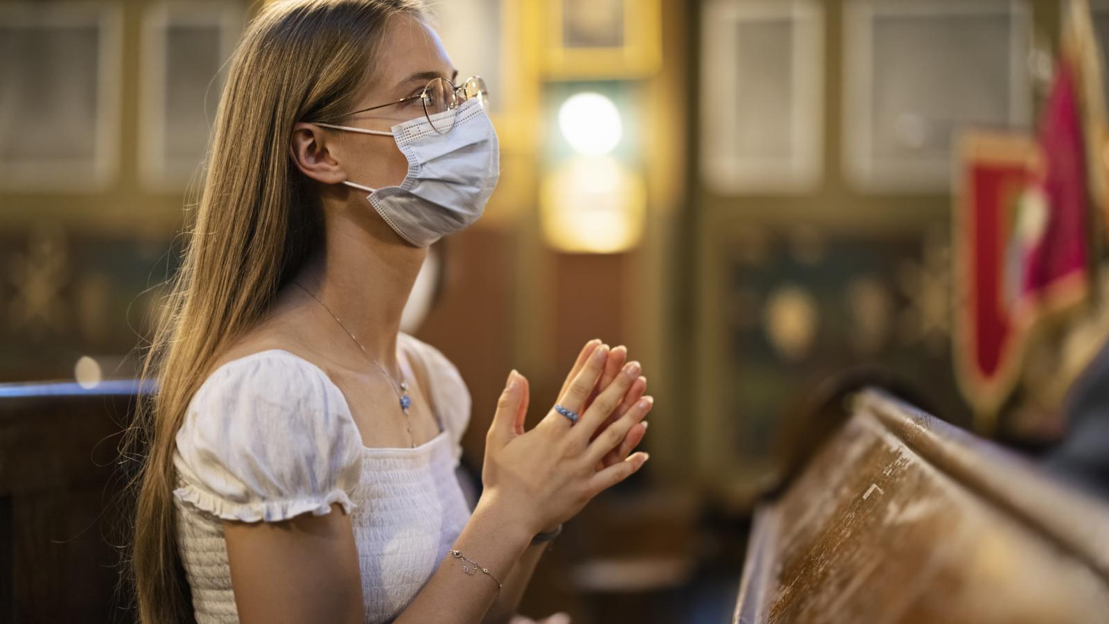 Girl praying in church with face mask