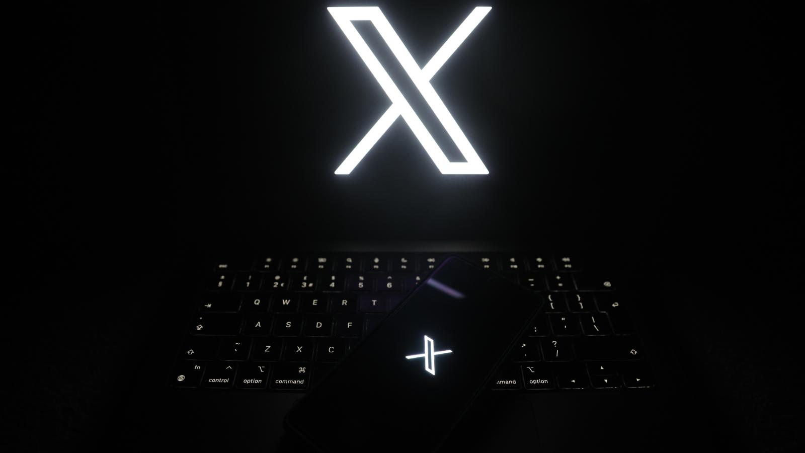 The logo of online social media site 'X' (formerly known as Twitter) is displayed on a smartphone and laptop