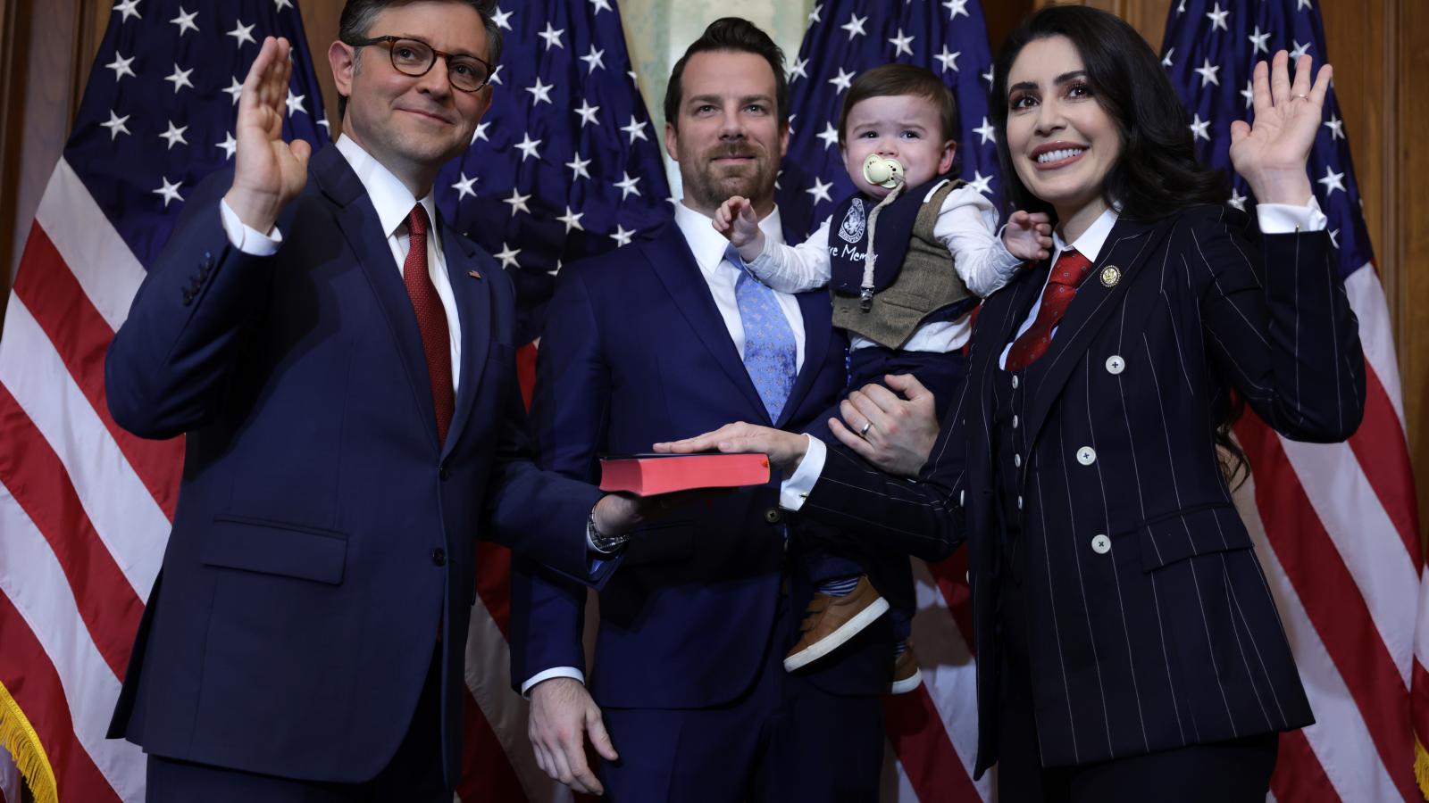 House Rep. Mike Johnson (R-LA) (L) participates in a ceremonial swearing-in with Rep. Anna Paulina Luna (R-FL) (R), her husband Andrew Gamberzky and her son at the U.S. Capitol on January 3, 2025 