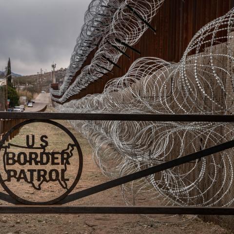 A metal fence marked with the US Border Patrol sign at the US/Mexico border fence, in Nogales, Arizona.