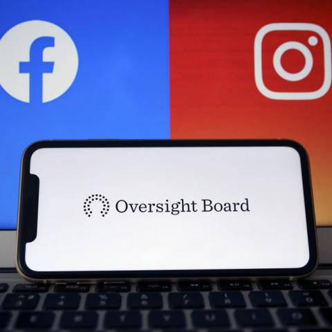 Oversight Board logo seen on phone, with Facebook and Instagram logos in background