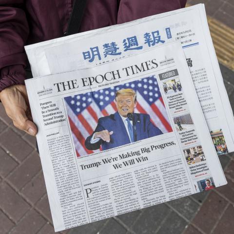 HONG KONG, CHINA - 2020/11/14: A woman distributes the multi-language newspapers The Epoch Times newspaper featuring on its front cover the former US President Donald J. Trump in Hong Kong. 