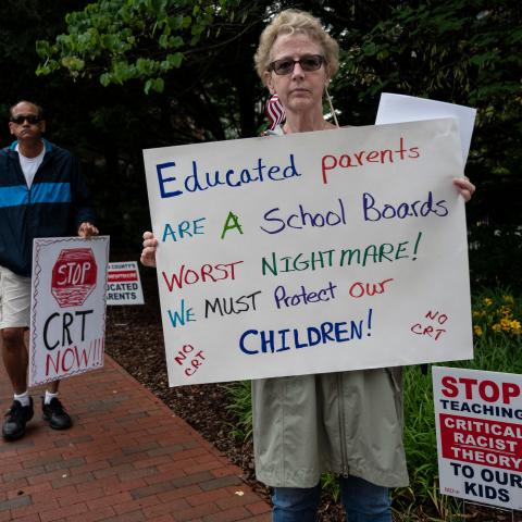 People hold up signs during a rally against "critical race theory" (CRT) being taught in schools at the Loudoun County Government center in Leesburg, Virginia on June 12, 2021.
