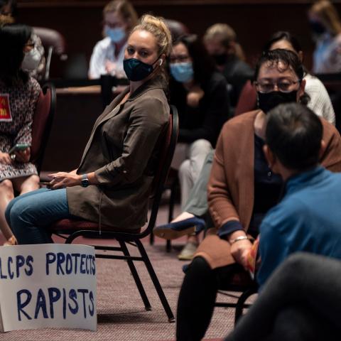 A woman sits with her sign during a Loudoun County Public Schools (LCPS) board meeting in Ashburn, Virginia on October 12, 2021.